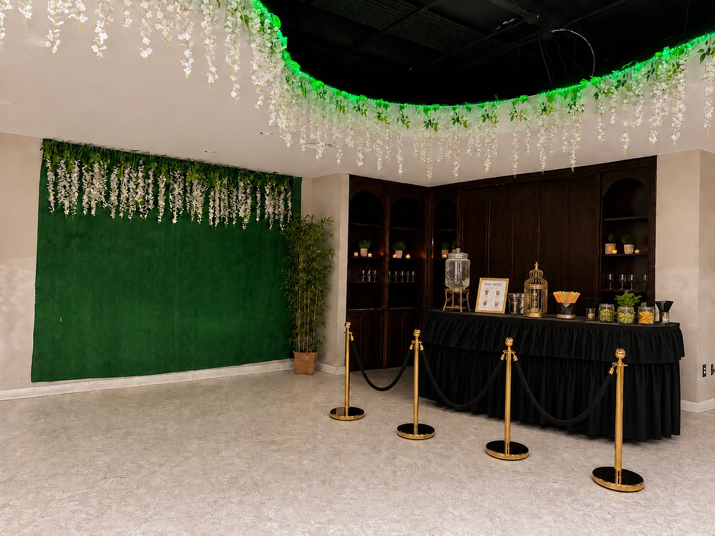 Montaje de bar con bebidas, detalles dorados y decoración floral blanca